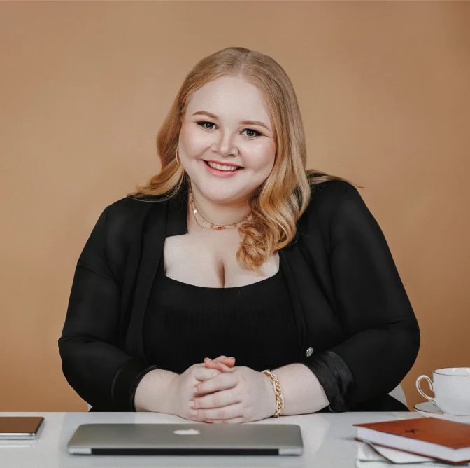Advogada Fernanda de Oliveira Pateis sorrindo à mesa de trabalho com notebook, agenda e café, oferecendo consultoria jurídica de confiança aos clientes