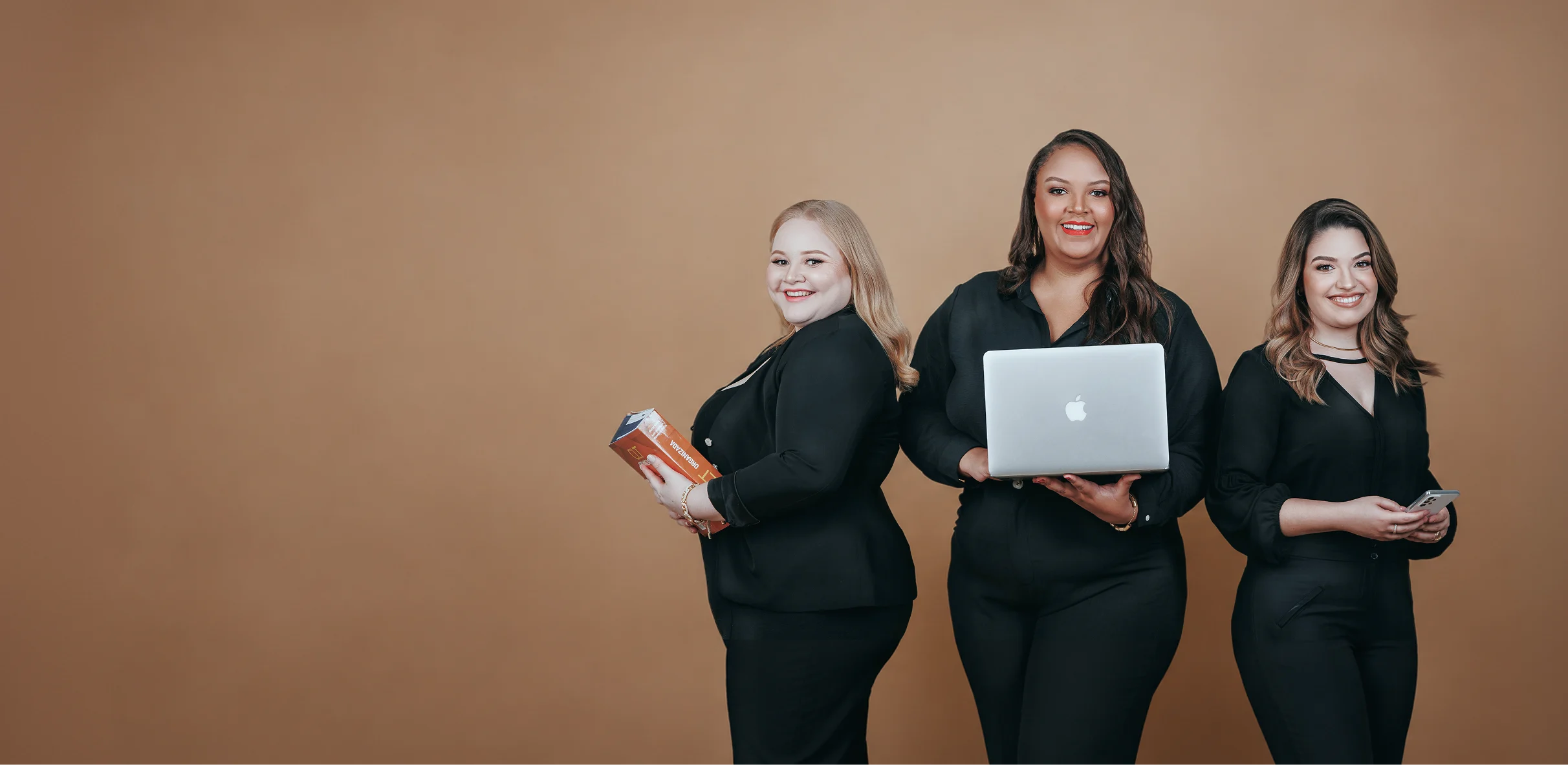 Equipe de advogadas da JOG Advocacia e Consultoria Jurídica em Maringá, de traje preto, com notebook, livro e celular, atuando em direito empresarial e societário